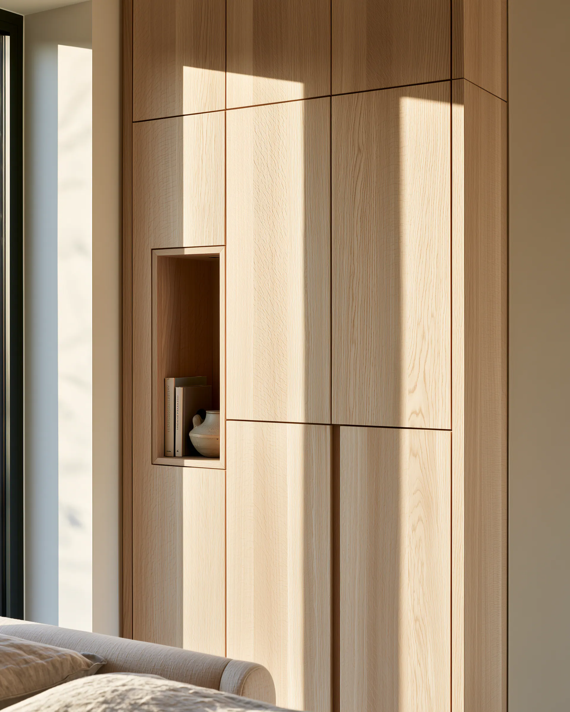 Full-height light wood bedroom cabinetry with a small display niche and consistent vertical grain